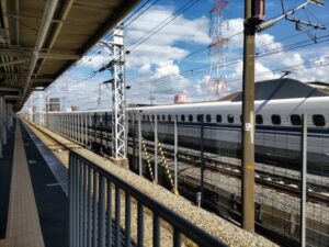 上牧駅から見える大阪方面の線路の隣で新幹線のぞみが通過している写真