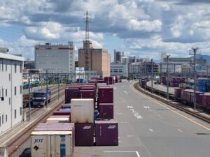 歩道橋から貨物ターミナル駅を見ると左側にはコンテナと桃太郎がいる写真