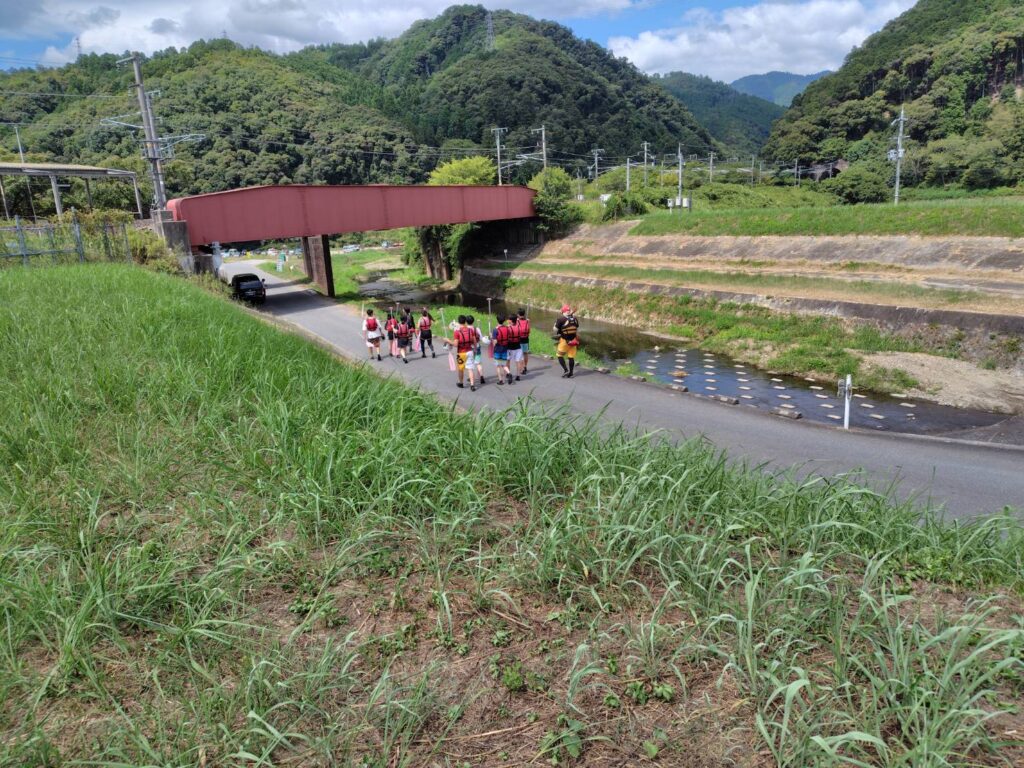 川沿いをゴムボートに乗る人たちが歩いている写真