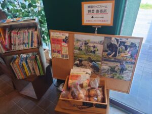 プラムイン城陽のロビーに子どもの絵本と野菜直売がある写真